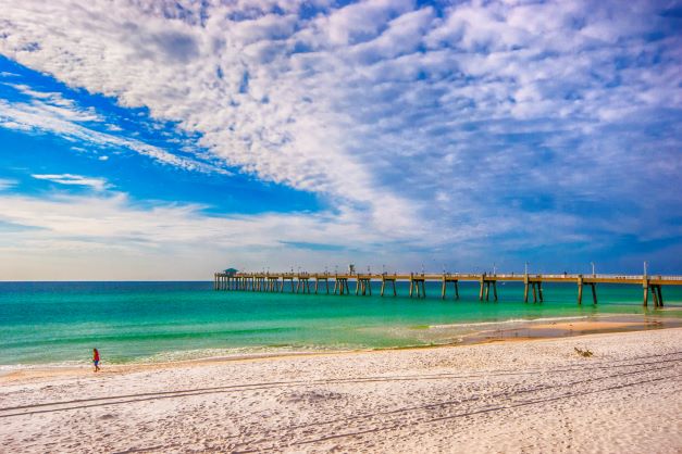 Beachgoer gazing out to sea, sugar-white sand, emerald waters, pier in the distance, Sandestin, Florida.