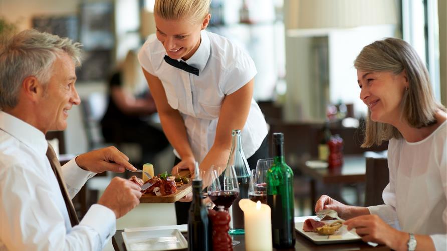 Wait staff serving mature couple at Hilton Grand Vacations