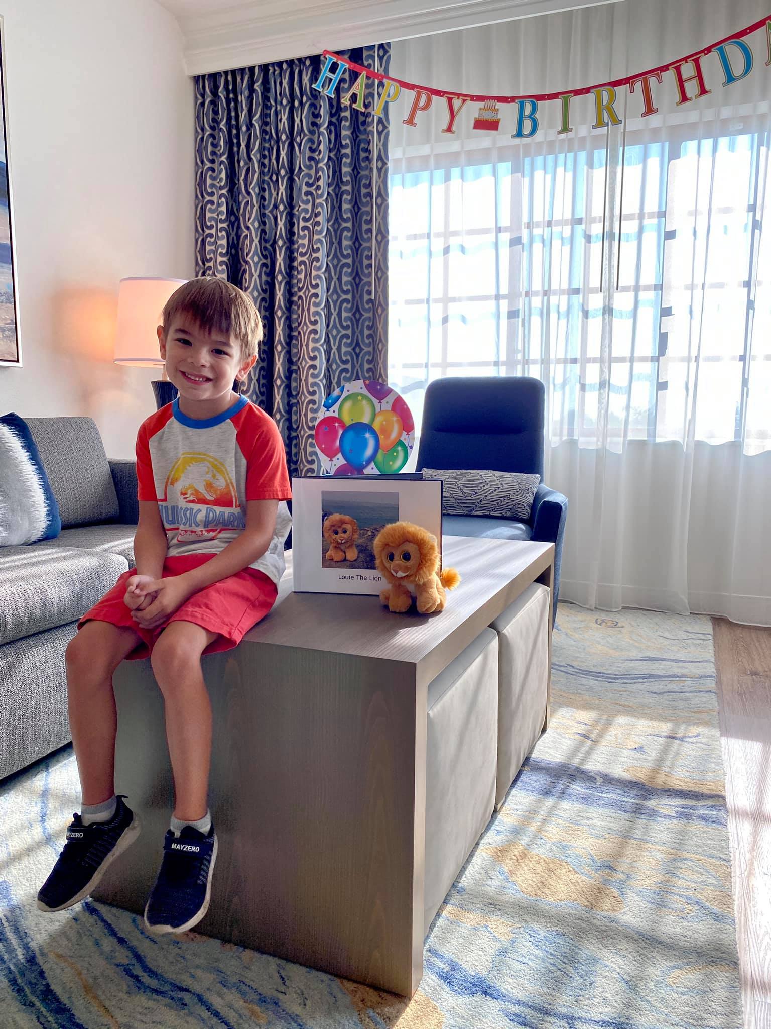 Jax and Little Louie posing with the book in their birthday decorated suite at Hilton Grand Vacations at MarBrisa in Carlsbad, California.