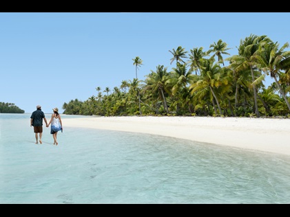 Couple walking hand in hand down the shore on One Foot Island Aitutaki, Cook Islands.