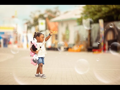 Little girl holding a Mini Mouse toy and popping bubbles at a theme park in Orlando, Florida. 