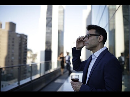 Man enjoying a beverage while taking in the New York City Skyline from the Owners Terrace at West 57th Street by Hilton Club, a New York City timeshare. 