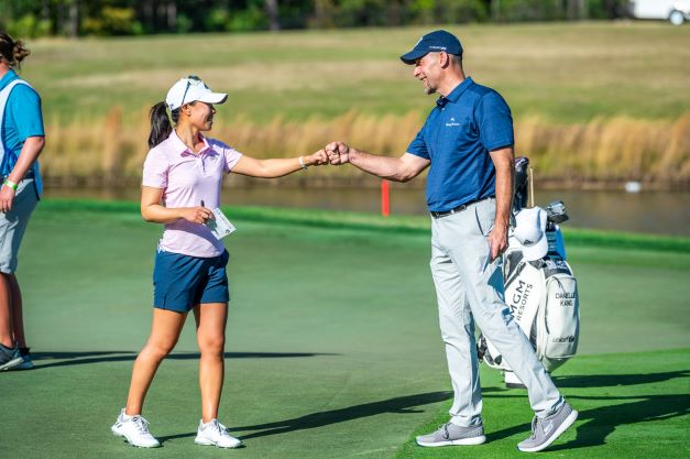 Celebrity and LPGA athlete smiling and fist bumping on the green at Hilton Grand Vacations Tournament of Champions. 