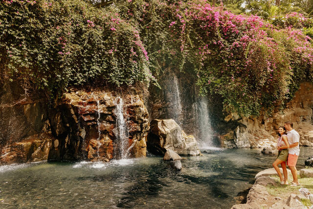 Couple embracing while enjoying the view of a waterfall in Maui, Hawaii. 