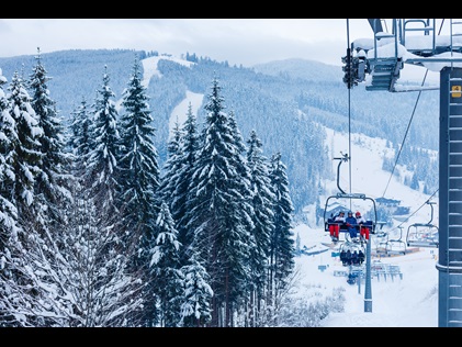 People riding a ski-lift on snow-covered ski-slopes.
