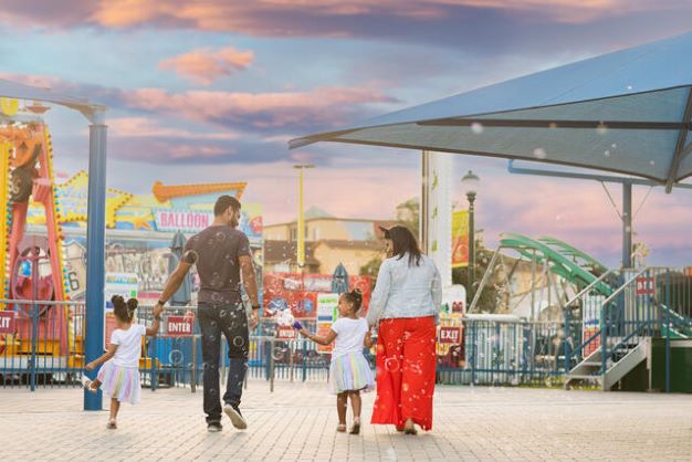 Family of four walking into Orlando theme park, Florida. 