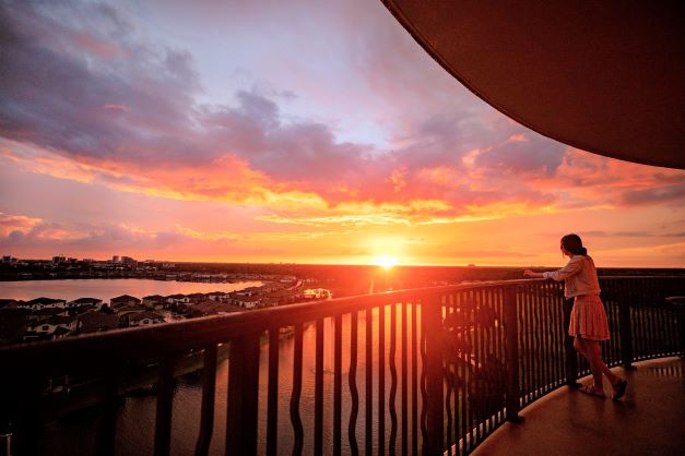 A woman standing on the balcony of Parc Soleil, a Hilton Grand Vacations Club, in Orlando at sunset