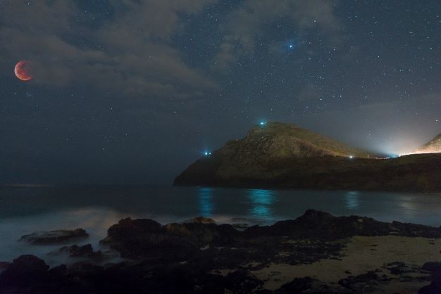 Gorgeous nighttime panorama of the Milky Way glowing above the Pacific ocean, mountains in the distance, Maui, Hawaii. 