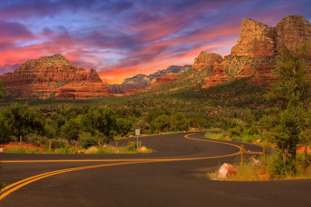 Wide open road winding through the Arizona desert with cotton candy sunset skies overhead, Sedona. 