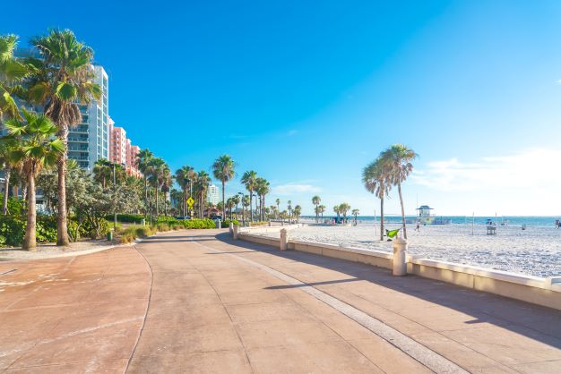 Beachside scene, beautiful beach and palm-tree lined paved walk way, clear blue skies, Clearwater Beach, Florida.