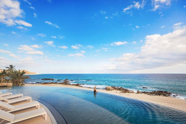 A woman in an infinity pool overlooks a beach at La Pacifica Los Cabos, a Hilton Club, in Los Cabos, Mexico