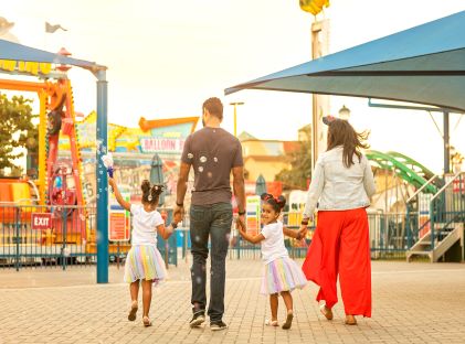 A Black family of four holds hands at a theme park in Orlando, Florida