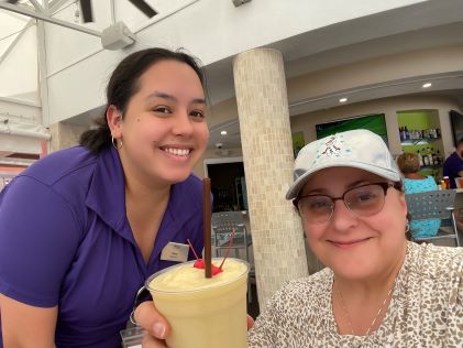 A Hilton Grand Vacations Member and Team Member smiling together by the pool at SeaWorld Orlando, a Hilton Grand Vacations Club