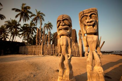 Tribal sculptures, palm trees in distance, Pu'uhonua o Hōnaunau National Historical Park, Big Island, Hawaii. 