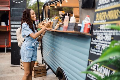 Smiling woman paying, food truck window. 