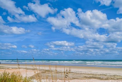 Calming beach scene, sand dunes, rolling waves, blue skies, Ormond Beach, Florida. 
