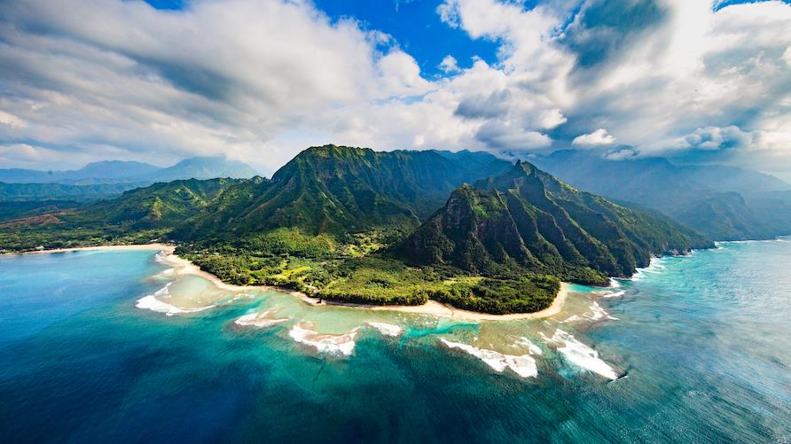 Breathtaking aerial view of the clear water and lush mountains of the Na Pali Coast in Kauai, Hawaii