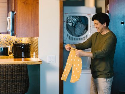 A parent folding laundry from an in-Suite washer and dryer, one of the amenities offered by Hilton Grand Vacations