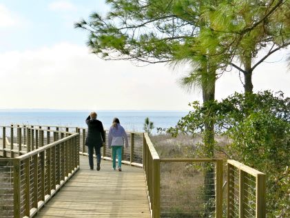 Two people take a wintery walk on a boardwalk on Hilton Head Island, South Carolina