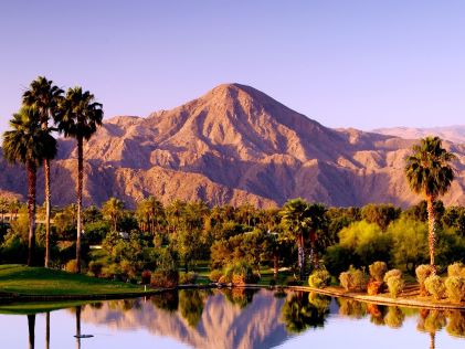 Mountain and pond with palm trees at sunset at Palm Springs, California