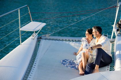 Couple on boat at sunset, sitting, embracing, gazing into sunset. 