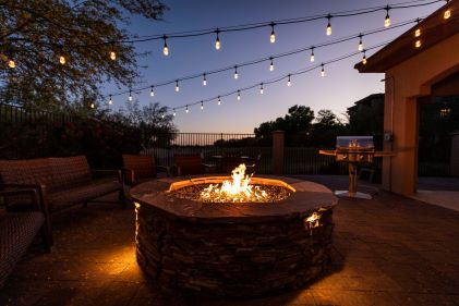 Relaxing scene, fire pit, market lights glowing against dusk sky. 