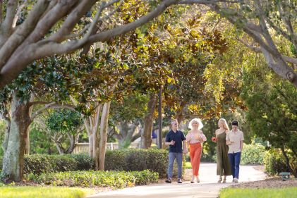 Multigenerational family strolling, stunning oak tree canopy overhead, Las Palmeras, a Hilton Grand Vacations Club, Orlando, Florida.