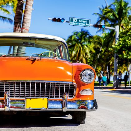 Close up, vintage car, palm trees in distance, blue skies overhead, South Beach, Miami, Florida. 