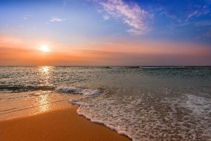 Stunning beach scene, sunrise, calm waves, blue skies. 