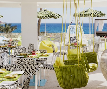 Green swinging chairs on colorful outdoor patio overlooking the Pacific Ocean at Mio Restaurant at La Pacifica Los Cabos, a Hilton Club