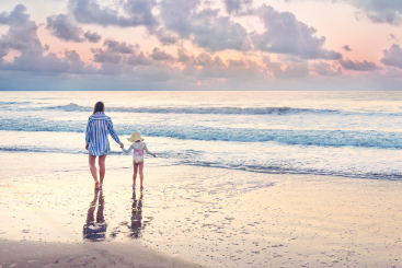 Mother and daughter walking along the Virginia Beach during the sunrise.