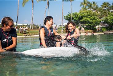 Couple swimming with dolphin in lagoon.